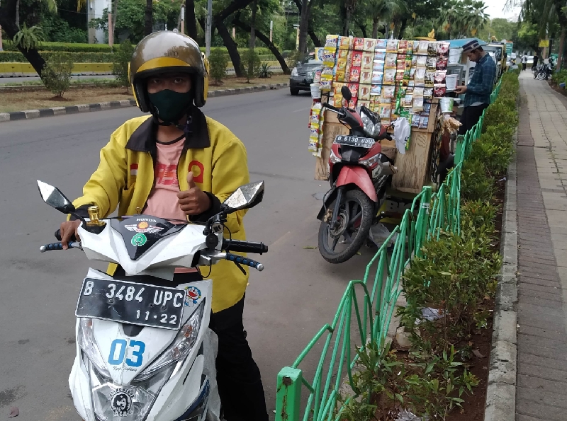 Rahmat dengan jaket ojek online Maxim warna kuning 