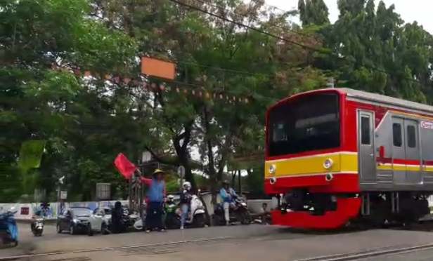 Warga berjaga di perlintasan sebidang kereta api saat KRL melintas di Jalan Pahlawan, Bulak Kapal, Bekasi, Jawa Barat, Rabu (25/11/2020).