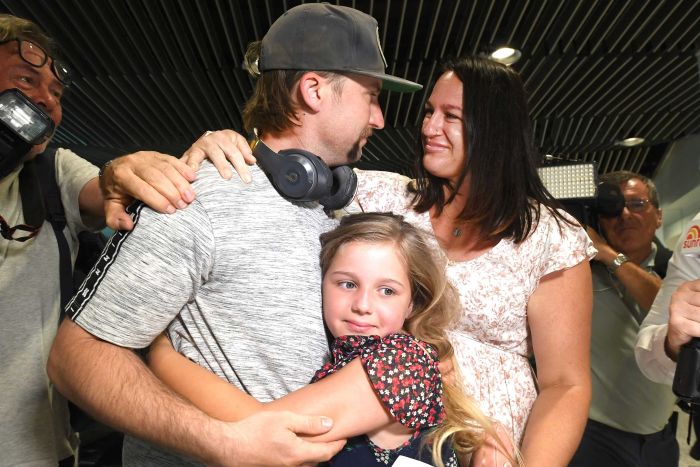 Penumpang Matt Jacovi (kiri) bertemu kembali dengan istrinya Ashley dan anak perempuan mereka, Payten setelah terpisah antara Sydney dan Brisbane selama perbatasan kedua negara bagian ditutup.  (Foto:AAP: Dave Hunt)