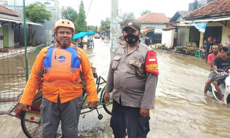 Bhabinkamtibmas POlsek Widasari dan personel Badan Penanggulangan Bencana Daerah Indramayu memonitor kondisi masyarakat terkait banjir. (Taryani)