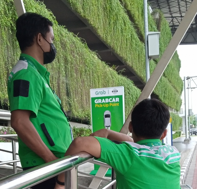 Petugas GrabCar sedang menanti konsumen. Foto: BeritaTrans.com/Aksi.id