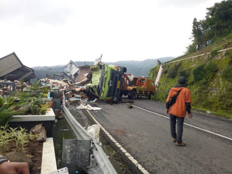 Mobil derek berupaya mengevakuasi truk tronton bermuatan minuman isotonik yang terjungkal di jalan tembus Magetan-Tawangmangu, tepatnya di depan RM Legender pada Jumat (22/1/2021) pukul 04.05 WIB. (Istimewa)