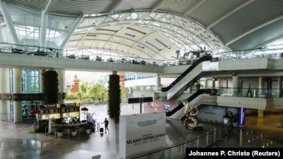 Seorang traveler berjalan menyusuri terminal kedatangan internasional yang hampir kosong dari bandara Gusti Ngurah Rai di tengah penyebaran Covid-19 di Bali, 1 April 2020. (Foto: REUTERS/Johannes P. Christo)