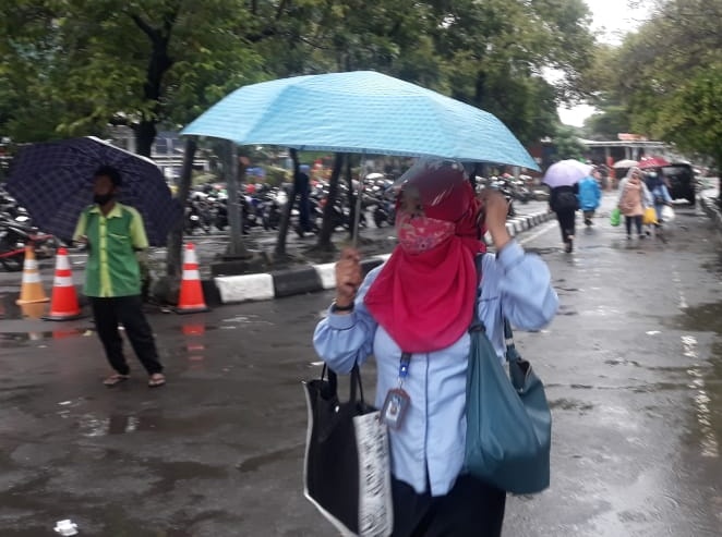 Dengan menggunakan payung, calon pengguna KRL Datangi Stasiun Bekasi. Foto: BeritaTrans.com/Aksi.id/bagas