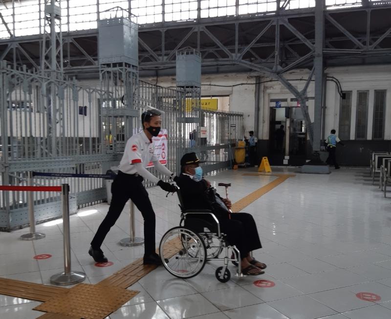 Petugas mendorong kursi roda yang dinaiki penumpang KRL yang tidak bisa jalan di Stasiun Tanjung Priok.