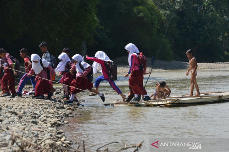 Pergi dan pulang menggunakan rakit bambu untuk menyeberangi sungai yang rawan buaya di pedalaman Desa Siron Krueng, Aceh Besar, Aceh.