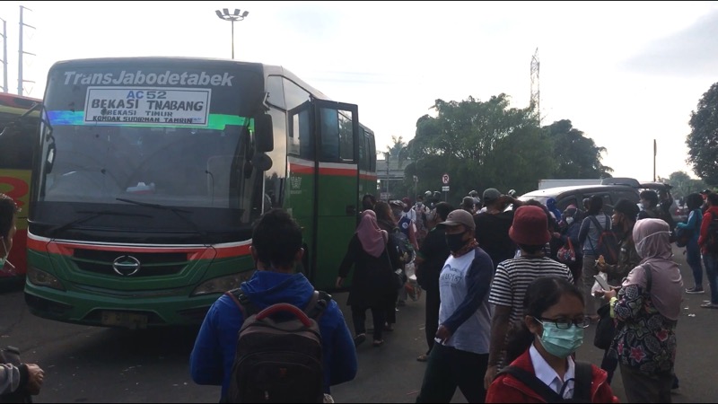 Penumpang menyerbu bus Kota yang tiba di depan Gerbang Tol Bekasi Timur, Senin (22/2/2021). Foto: BeritaTrans.com