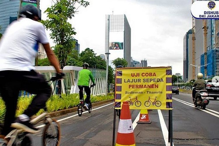 Papan pengumuman uji coba pembatas jalur sepeda permanen terlihat di kawasan Sudirman, Jakarta.