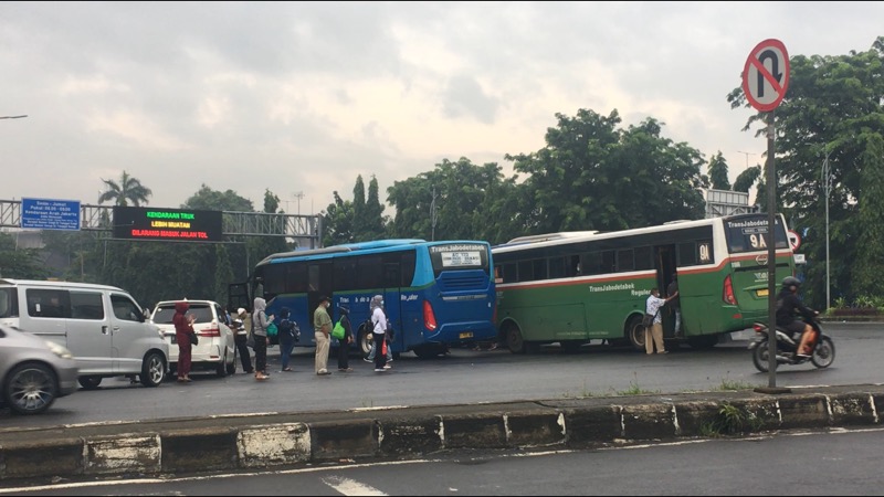 Penumpang dan bus Kota disisi jalan tepat depan Gerbang Tol Bekasi Timur, Rabu (10/3/2021). Foto: BeritaTrans.com.