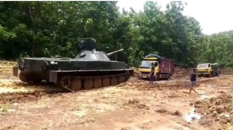Potongan gambar, tank TNI menarik sebuah truk yang terjebak di jalan berlumpur.