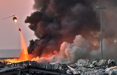 Sebuah helikopter berusaha memadamkan api dalam ledakan yang terjadi di pelabuhan Beirut, ibu kota Lebanon, pada 4 Agustus 2020.(STR via AFP)