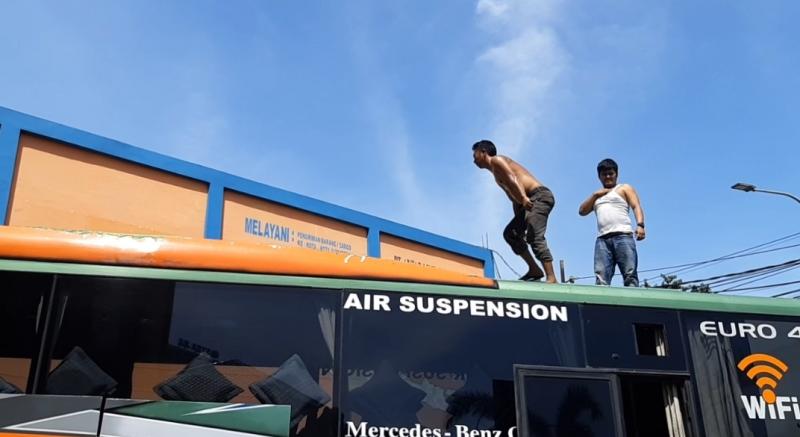 Hendra bersama sopir bus ALS, Nasron naik di atap bus untuk menaikkan barang bawaan penumpang.