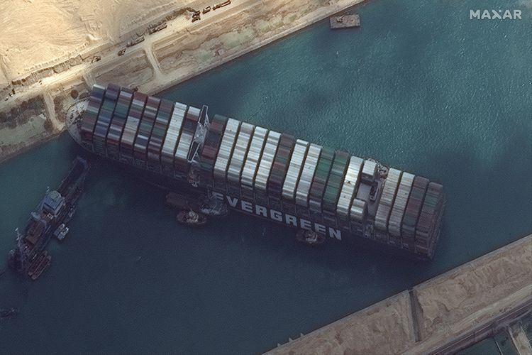 Foto satelit dari Maxar Technologies memperlihatkan kapal kargo MV Ever Given masih terjebak diagonal di Terusan Suez, dekat Suez, Mesir, pada Jumat (26/3/2021). Akibat Terusan Suez macet, lebih dari 200 kapal antre masuk dan beberapa di antaranya mulai berputar mengubah rute.
