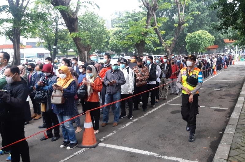 Petugas berjaga mengamankan antrean pengguna KRL di Stasiun Bekasi, Senin (5/4/2021).