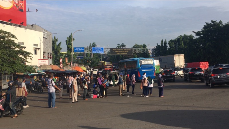 Calon penumpang tengah menunggu bus Kota tiba di depan Gerbang Tol Bekasi Timur, Senin (12/4/2021) pagi. Foto: BeritaTrans.com.