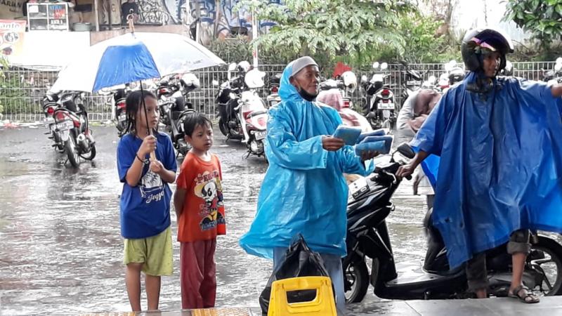 Dengan bantuan ojek payung, traveler menerabas hujan untuk naik KRL dari Stasiun Sudimara. Foto: BeritaTrans.com dan Aksi.id.