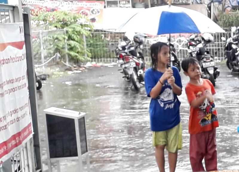 Fatma (9), dan adiknya,Danu (7), jajakan ojek payung di Stasiun Sudimara, Tangerang Selatan, Kamis (15/4/2021) sore, Foto: BeritaTrans.com dan Aksi.id.