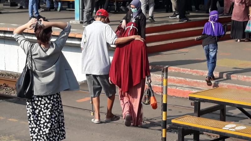 Dengan menggunakan tongkat, pria itu dituntun seorang perempuan saat hendak naik KRL di Stasiun Manggarai, Jumat Pagi, 23 April 2021. Foto: BeritaTrans.com dan Aksi.id.