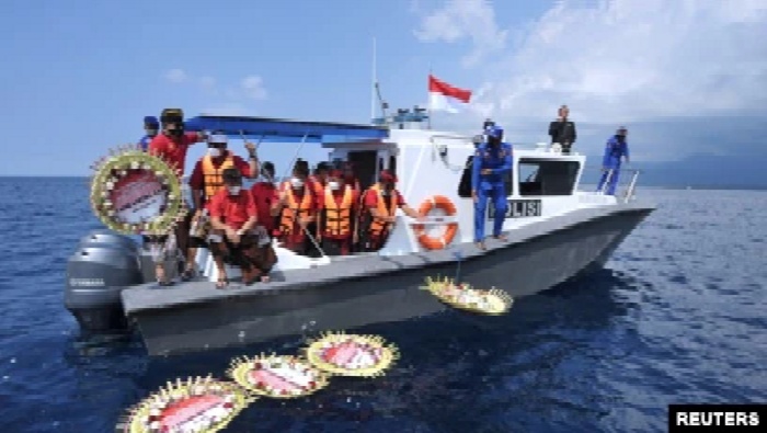 Warga melempar bunga dan kelopak bunga dengan nama awak kapal selam KRI Nanggala-402 yang tenggelam di laut, di dekat Labuhan Lalang, Bali, 26 April 2021. (Foto: Antara/Fikri Yusuf via Reuters)