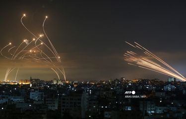 Sistem pertahanan rudal Iron Dome Israel (kiri) mencegat roket (kanan) yang ditembakkan oleh gerakan Hamas menuju Israel selatan dari Beit Lahia di Jalur Gaza utara seperti yang terlihat di langit di atas Jalur Gaza pada 14 Mei 2021(AFP PHOTO/ANAS BABA)