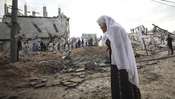 Warga Palestina di tengah bangunan yang hancur akibat gempuran Israel. (AFP/MAHMUD HAMS)