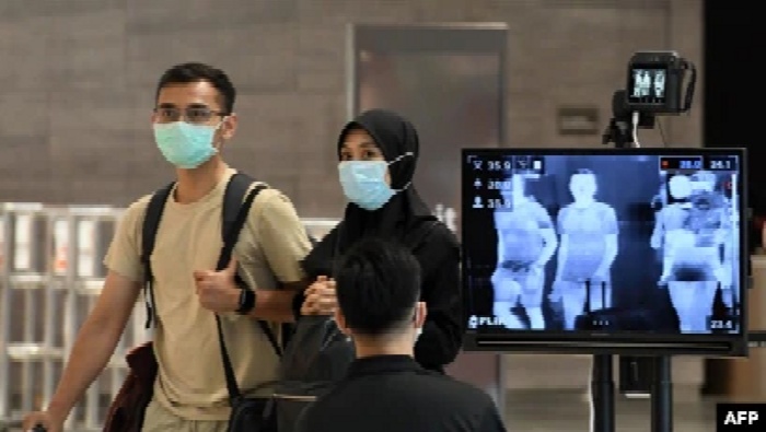 Sepasang suami istri, mengenakan masker di tengah kekhawatiran tentang penyebaran virus corona baru COVID-19, berjalan melewati pemeriksaan pemeriksaan suhu di Bandara Internasional Changi di Singapura, 27 Februari 2020. (Foto: AFP)