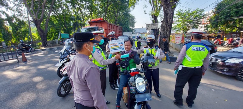 Sejumlah anggota Polsek Bekasi Kota membagikan masker gratis ke sejumlah warga yang melintas, Jumat (28/5/2021). Foto: Polrestro Bekasi Kota.
