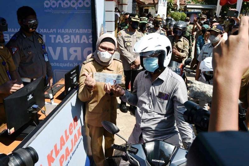 Bupati Indramayu Hj. Nina Agustina saat menyerahkan helm kepada wajib pajak yang telah membayar pajak kendaraan bermotor di Samsat Haurgeulis, Indramayu, Jawa Barat, Senin (07/06/2021). (Taryani)