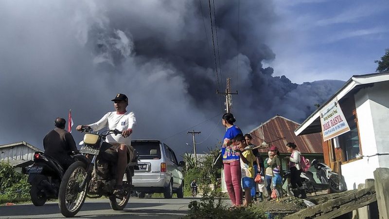 Sejumlah pengendara melintas di Jalan Karo-Langkat dengan latar belakang Gunung Sinabung yang menyemburkan material vulkanik di Desa Kutarayat, Naman Teran, Karo, Sumatera Utara, Kamis (13/8).. Foto: Antara.