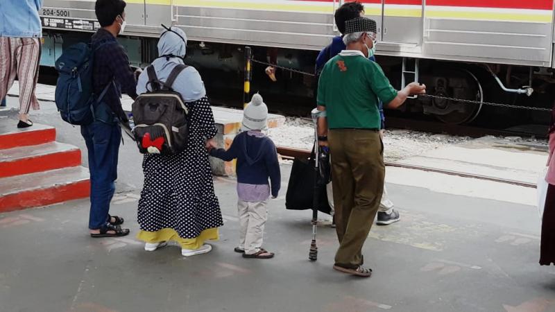 Pria berambut silver dengan mengenakan tongkat berjalan di antara penumpang KRL lain di Stasiun Manggarai.
