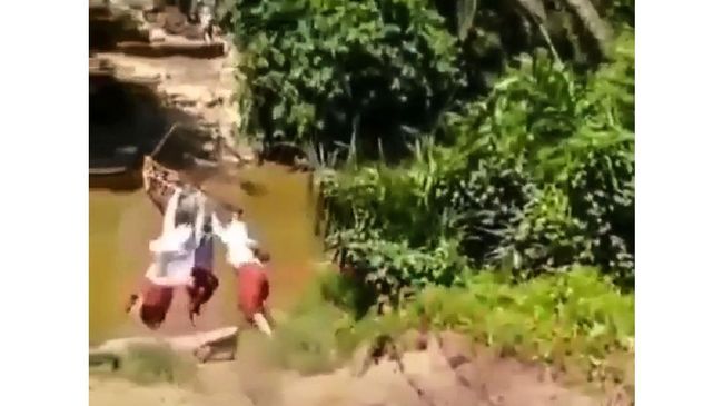 Sejumlah anak SD di Riau bergelantungan di keranjang flying fox melintasi sungai demi memangkas waktu menuju sekolahnya.