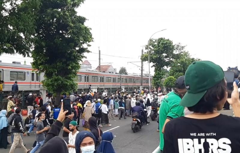 KRL tetap melintas saat terjadi aksi masa di jalan raya Bekasi oleh pendukung Habib Rizieq Sihab pada Kami (24/6/2021).