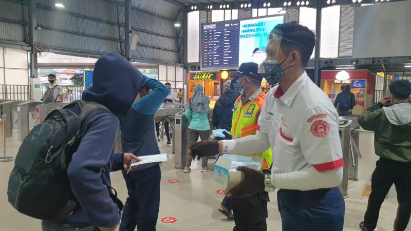 Petugas KAI Commuter membagikan masker kepada pengguna KRL pada sosialisasi penggunaan masker ganda.(foto:Istimewa)