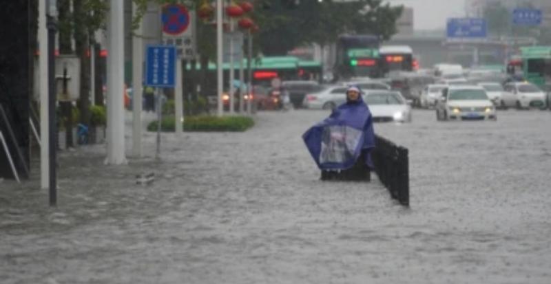 Seorang pejalan kaki mengenakan jas hujan mengarungi banjir di sebuah jalan di Zhenzhou, Henan, China, Selasa, 20 Juli 2021. (Foto: cnsphoto via Reuters)