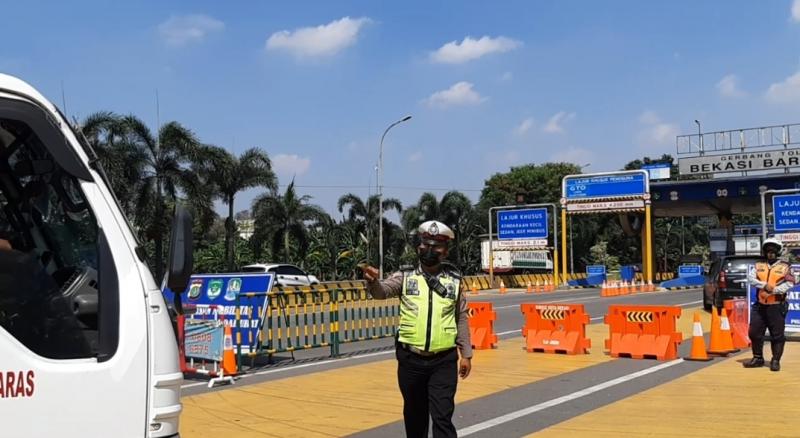 Petugas yang berjaga di Gerbang Tol Bekasi Barat 1 meminta sejumlah pengendara tidak sesuai untuk putar arah, Senin (26/7/2021).