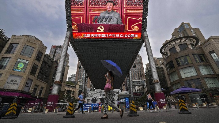 Orang-orang berjalan melewati layar video besar di luar pusat perbelanjaan yang memperlihatkan Presiden China Xi Jinping berbicara.