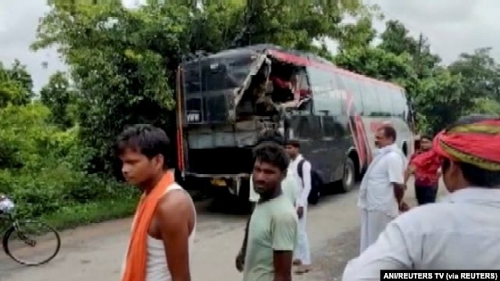 Orang-orang berdiri di lokasi kecelakaan setelah sebuah truk yang melaju kencang menabrak bus tingkat yang penuh sesak, di distrik Barabanki, Uttar Pradesh, India, 28 Juli 2021. (Foto: ANI/REUTERS TV via REUTERS)