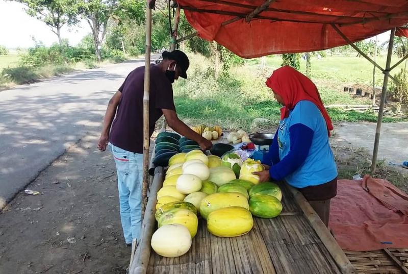 Penjual semangka di tepi jalan kabupaten Blok Pecuk, Minggu (22/08/2021) tampak sedang melayani salah seorang pembeli. (Taryani)  