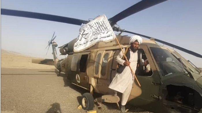 Pejuang Taliban berpose dengan helikopter Blackhawk angkatan udara Afghanistan buatan AS di lapangan terbang Kandahar yang direbut. (Foto:Istimewa)