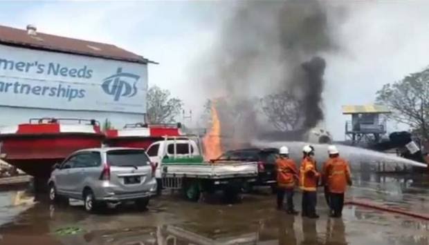 Petugas pemadam kebakaran berjibaku memadamkan truk tangki elpiji dan dua mobil lain di area PT Dok dan Perkapalan Surabaya, Senin (30/8/2021).