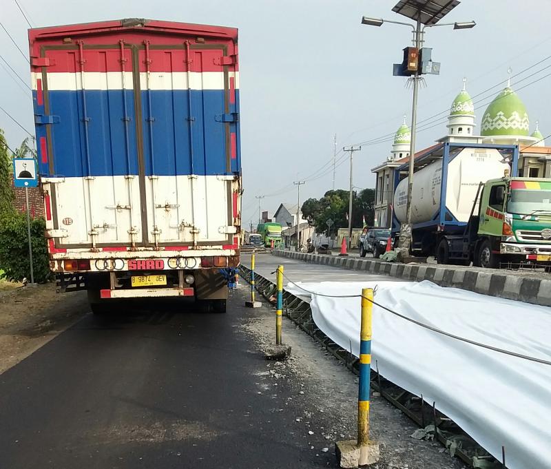 Kendaraan boks melaju disamping proyek jalan beton di jalan Pantura wilayah Kabupaten Subang, Jawa Barat. (Taryani)
