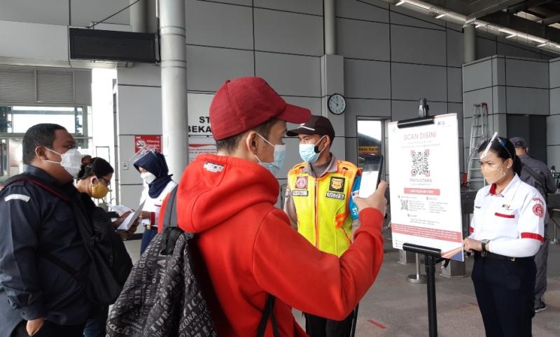 Penumpang melakukan scan kode QR menggunakan Aplikasi PeduliLindungi saat hendak mau naik KRL di Stasiun Bekasi Timur. 