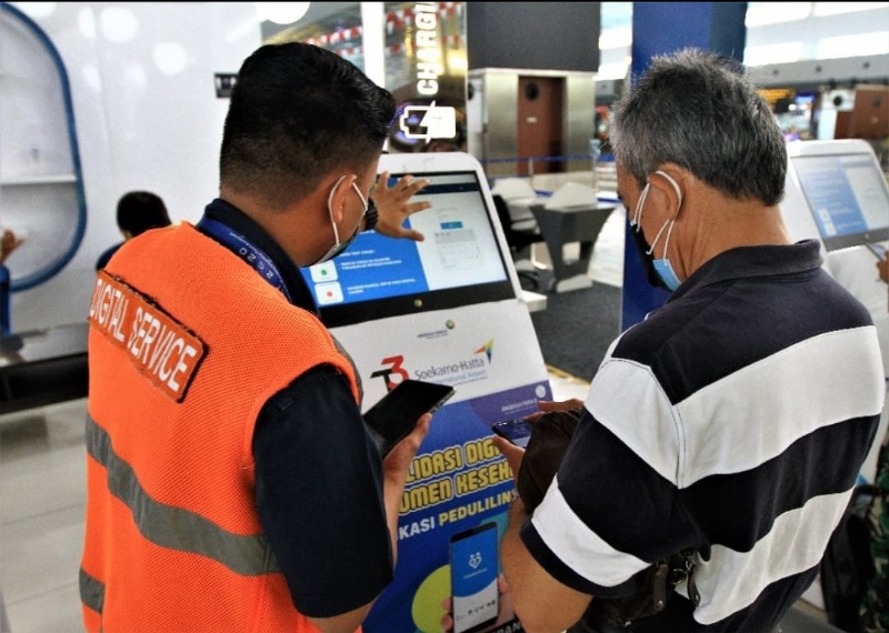 Petugas membantu calon penumpang dalam menggunakan aplikasi PeduliLindungi di Bandara Angkasa Pura II