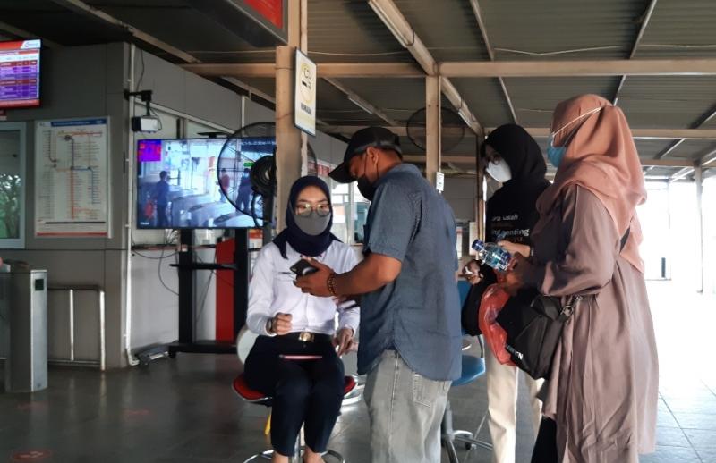 Penumpang KRL menunjukan hasil scan kode QR Aplikasi Peduli Lindungi kepada petugas sebagai syarat naik KRL dari Stasiun Bekasi, Ahad (3/10/2021).