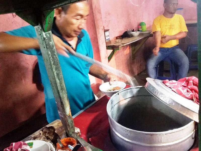 Pak Rali menuangkan kuah sop kambing di mangkuk pesanan pelanggan. (Taryani)    