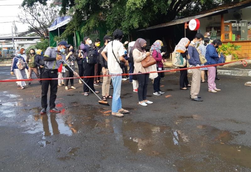 Petugas kebersihan Stasiun Bekasi bekerja di antara penumpang KRL yang antre pada Senin (18/10/2021).