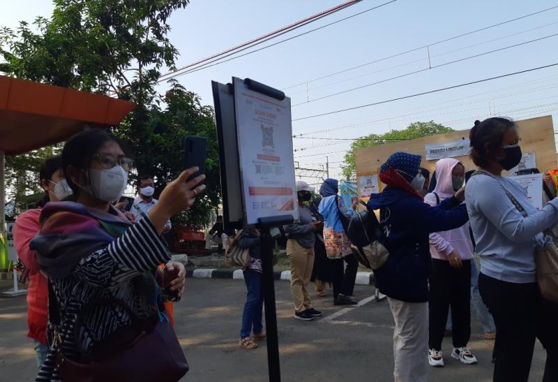 Masyarakat penumpang KRL melakukan scan kode QR Aplikasi PeduliLindungi sebagai syarat perjalanan menggunakan moda transportasi umum.