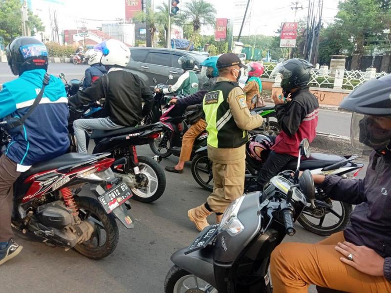 Seorang anggota Linmas di Kota Cirebon menegur pengendara sepeda motor. (Ist.)