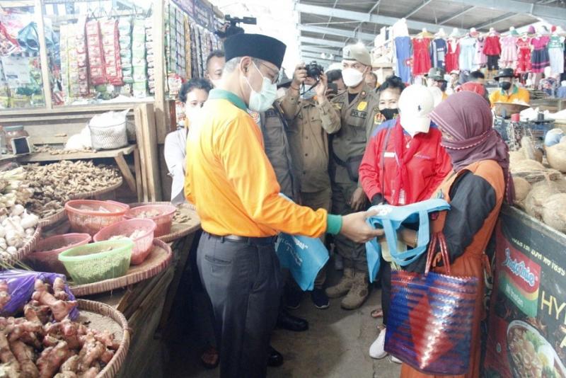 Bupati Temanggung memberikan kantong plastik kepada ibu-ibu yang sedang berbelanja di pasar guna menekan sampah. (Ist.) 