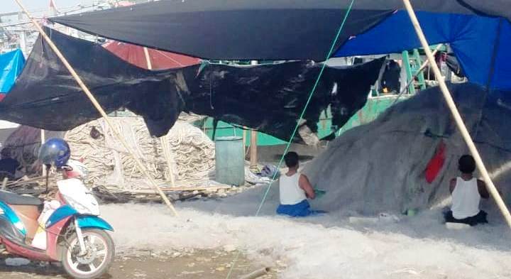 Anak buah kapal (ABK) di Indramayu ini tengah memperbaiki jaring yang robek setelah dipergunakan menangkap ikan di laut. (Taryani) 